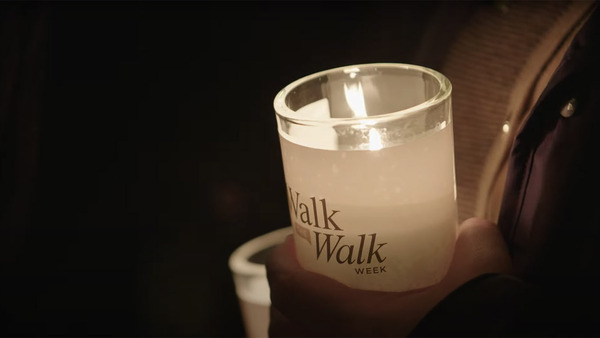 A close-up photo of a lit glass candle with Walk the Walk week printed on it