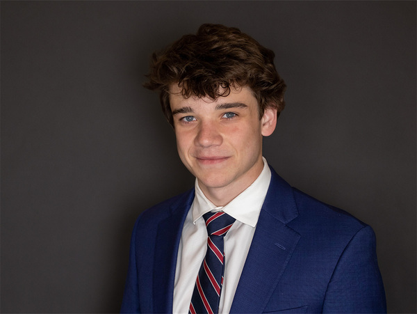 White male with tie and suit smiles at camera.