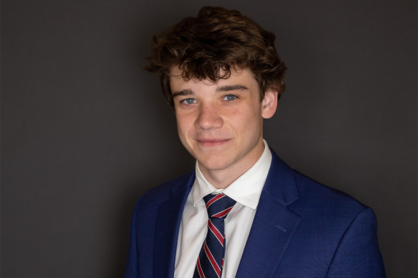 White male with tie and suit smiles at camera.