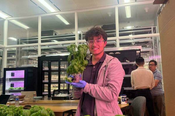 Notre Dame engineering student Johan Rengifo holds up basil plant he helped grow at Farmacy.