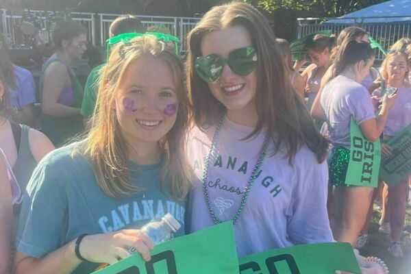 Abbey Donahue '25 holding a Go Irish sign with a friend at a Notre Dame tailgate.